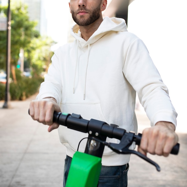 Hombre con sudadera con capucha rining un scooter eléctrico