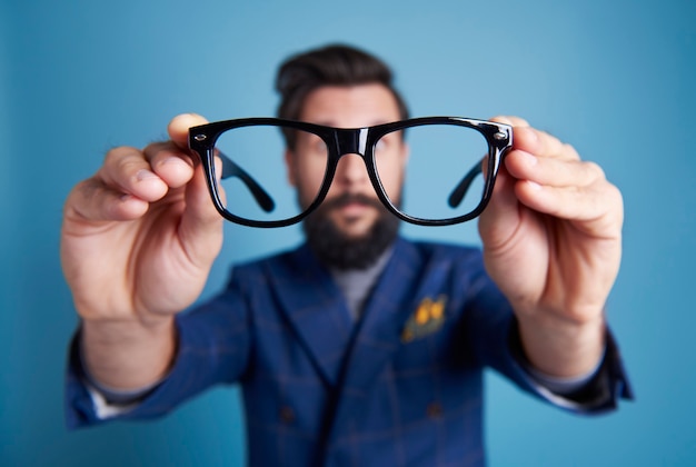 Hombre sujetando anteojos frente a su cara