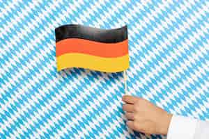 Foto gratuita hombre sujetando la bandera alemana con fondo estampado