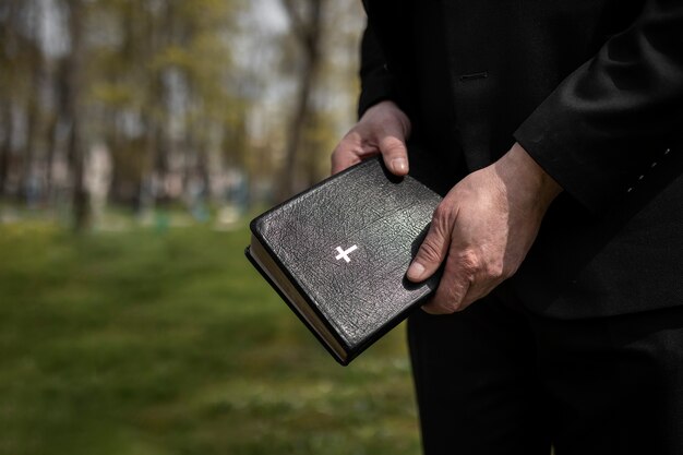 Hombre sujetando la biblia en el cementerio con espacio para copiar