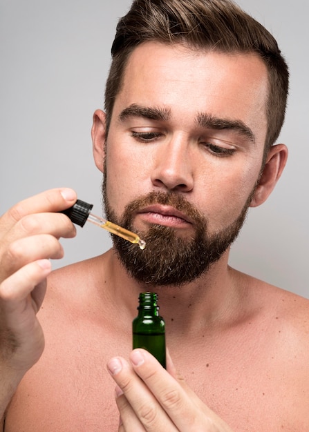 Hombre sujetando una botella de aceite facial