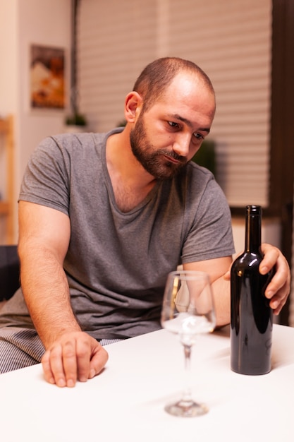 Hombre sujetando una botella de vino tinto decepcionado por esposa infiel