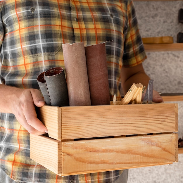 Hombre sujetando una caja de madera con herramientas