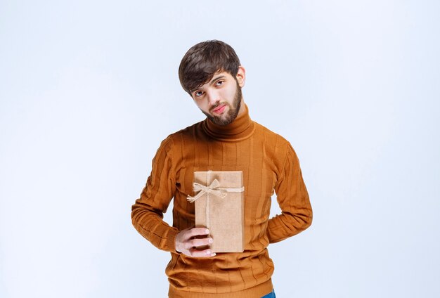 Hombre sujetando una caja de regalo de cartón y presentándola