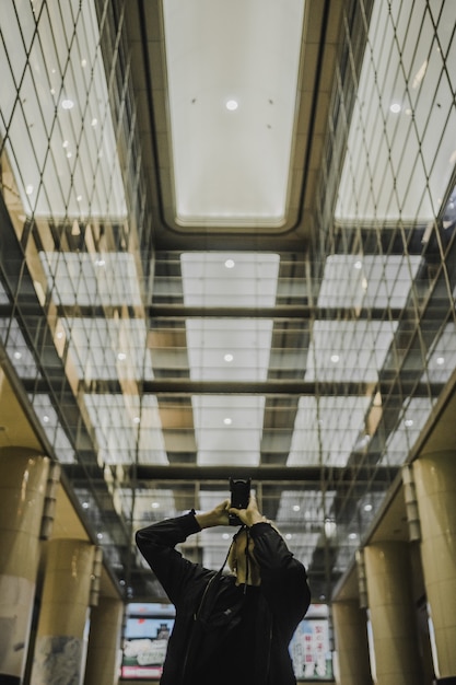 Hombre sujetando una cámara DSLR mientras toma una foto en el pasillo