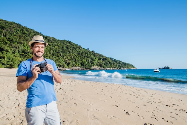 Foto gratuita hombre sujetando cámara en la playa