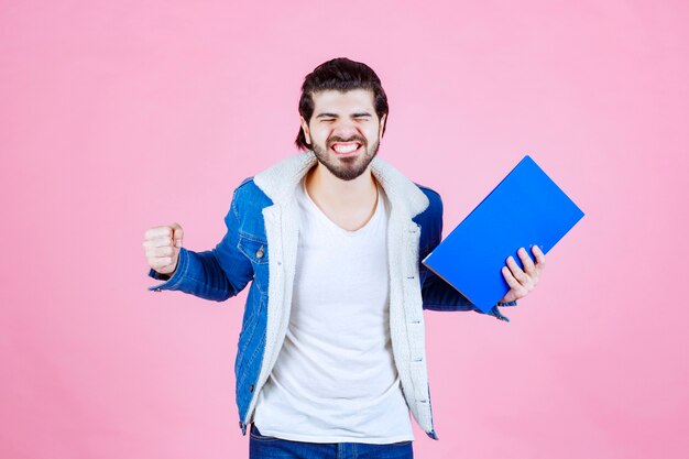 Hombre sujetando una carpeta azul y mostrando su puño