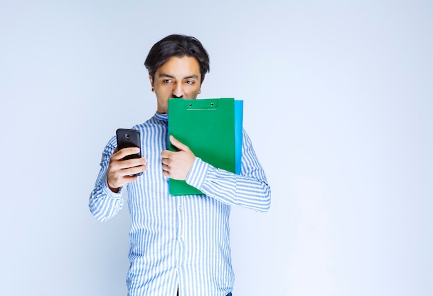 Hombre sujetando carpetas verdes y tomando su selfie. Foto de alta calidad