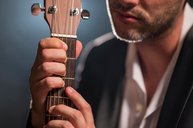 Hombre sujetando las cuerdas de una guitarra