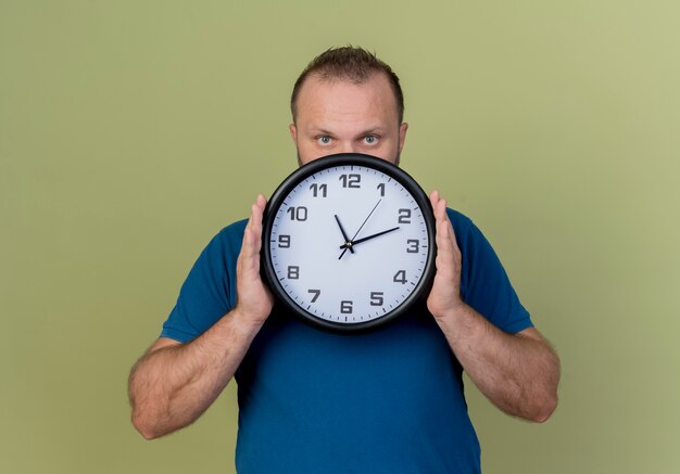 Hombre sujetando eslavo adulto reloj mirando desde detrás del reloj