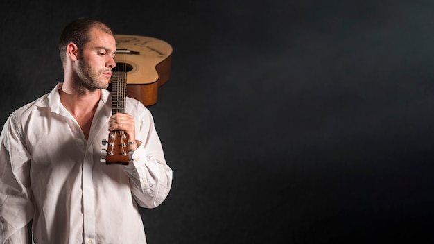 Hombre sujetando el espacio de copia de guitarra acústica