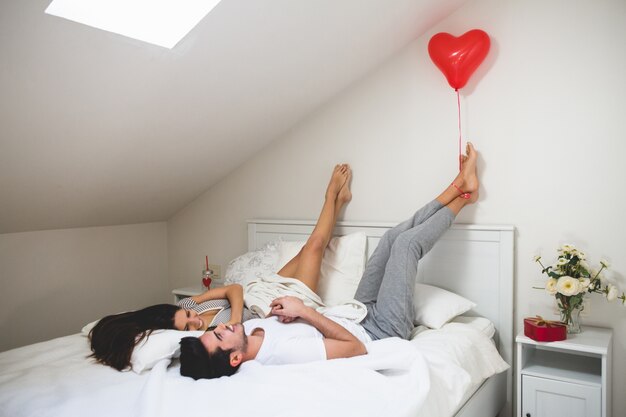 Hombre sujetando un globo con forma de corazón con los pies