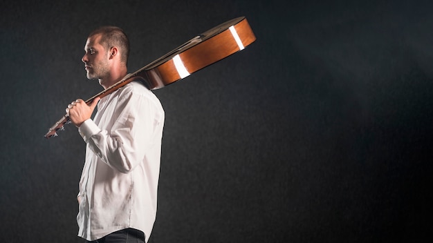 Foto gratuita hombre sujetando la guitarra acústica en estudio