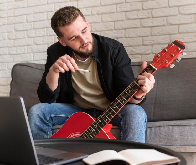 Hombre sujetando la guitarra de tiro medio