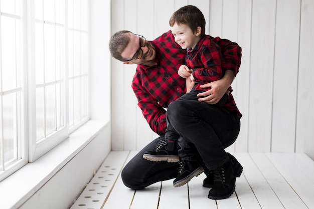 Hombre sujetando hijo en el día del padre enfrente de pizarra