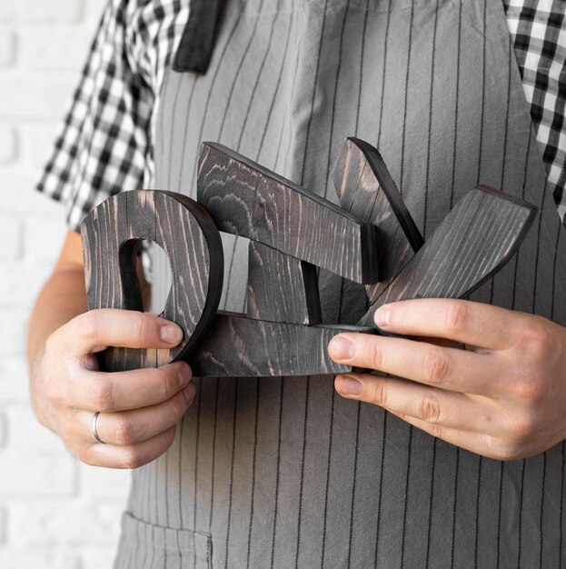 Hombre sujetando letras diy hechas de madera de cerca