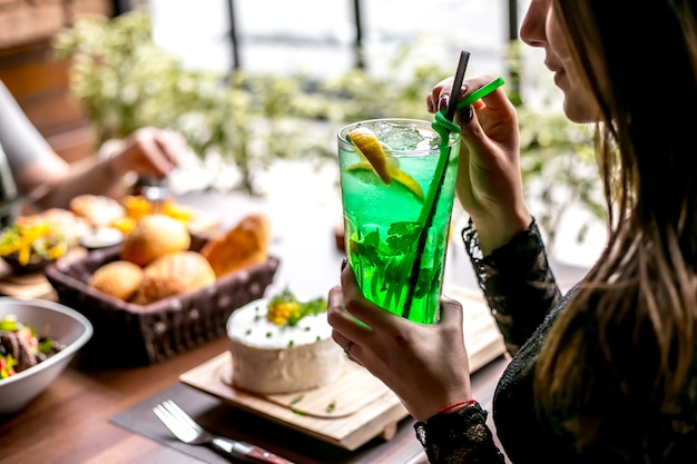 Hombre sujetando limonada de estragón con vista lateral de limón