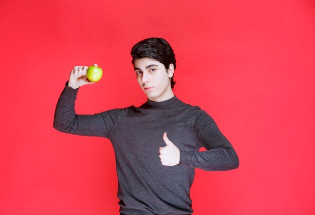 Hombre sujetando una mandarina verde y disfrutándola