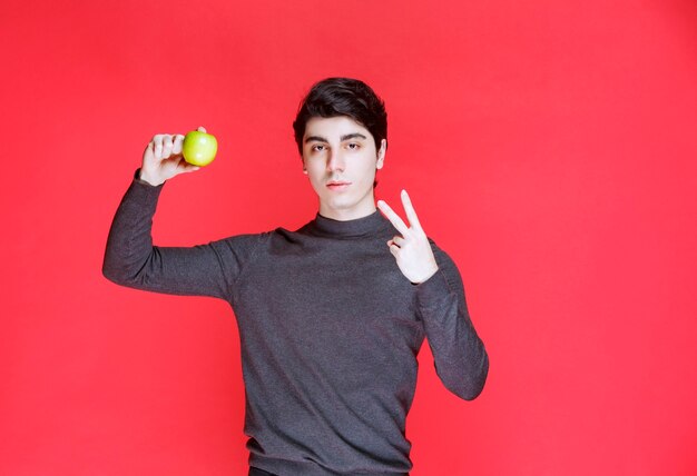 Hombre sujetando una mandarina verde y disfrutándola