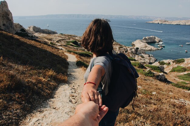 Hombre sujetando la mano de la mujer cerca del mar durante el día