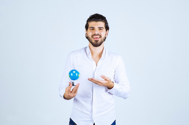 Hombre sujetando un mini globo y mirándolo