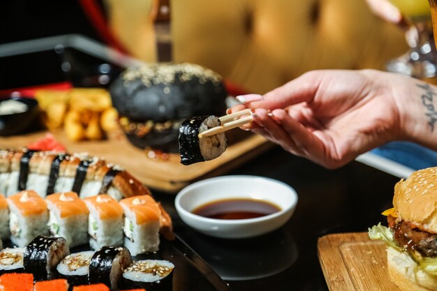 Hombre sujetando palos maguro maki ginger wasabi vista lateral