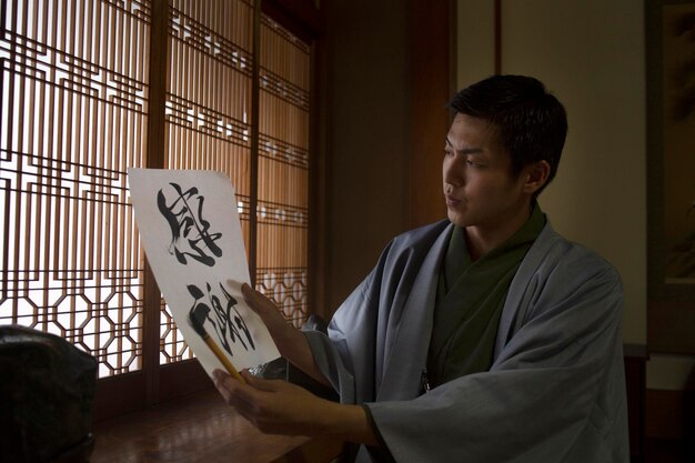 Hombre sujetando un papel con letra japonesa