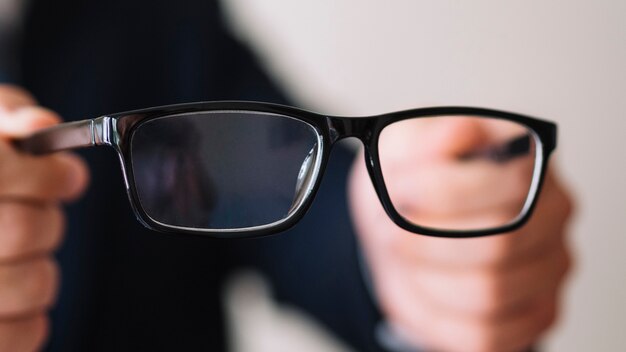 Hombre sujetando un par de gafas con marco negro