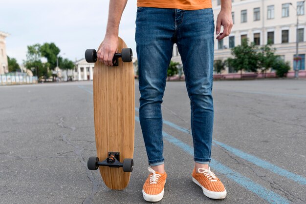 Hombre sujetando una patineta en la calle