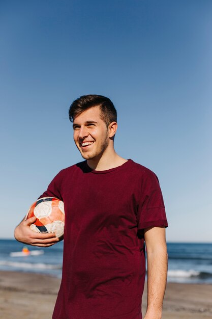 Hombre sujetando pelota en la playa