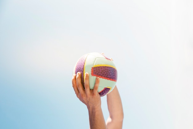 Hombre sujetando pelota sobre fondo de cielo