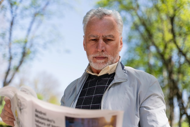 Hombre sujetando un periódico de tiro medio