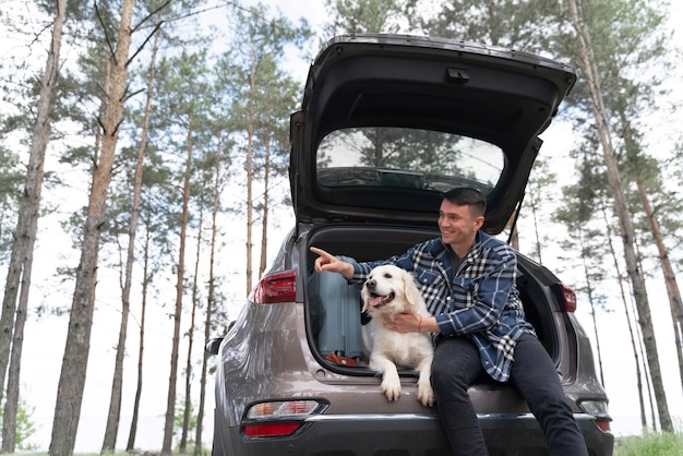 Hombre sujetando un perro de tiro medio en el maletero