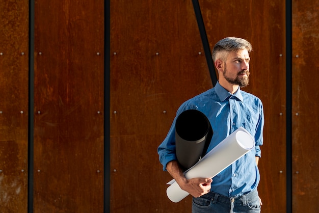 Hombre sujetando plan de construcción con espacio de copia