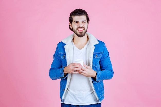 Hombre sujetando y presentando una nueva taza de café desechable