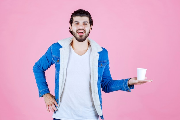 Hombre sujetando y presentando una nueva taza de café desechable