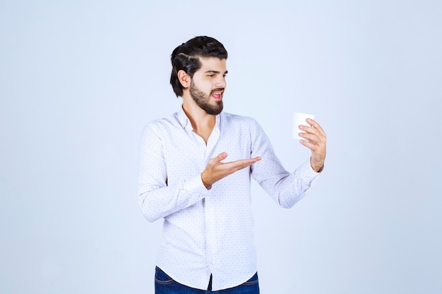 Hombre sujetando y promocionando una taza de café o café