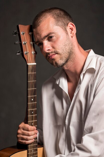 Hombre sujetando su cabeza en el clavijero de la guitarra