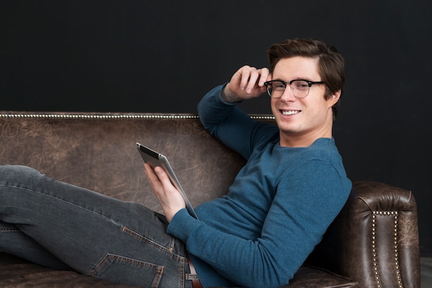 Foto gratuita hombre sujetando su tableta mientras permanece en su sofá
