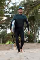 Foto gratuita hombre sujetando una tabla de surf al aire libre