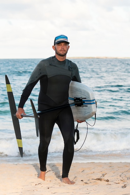 Foto gratuita hombre sujetando una tabla de surf al aire libre