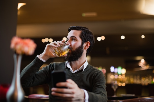 Hombre sujetando el teléfono móvil y tomar una copa