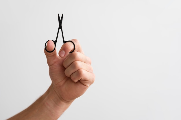 Hombre sujetando las uñas con tijeras con espacio de copia