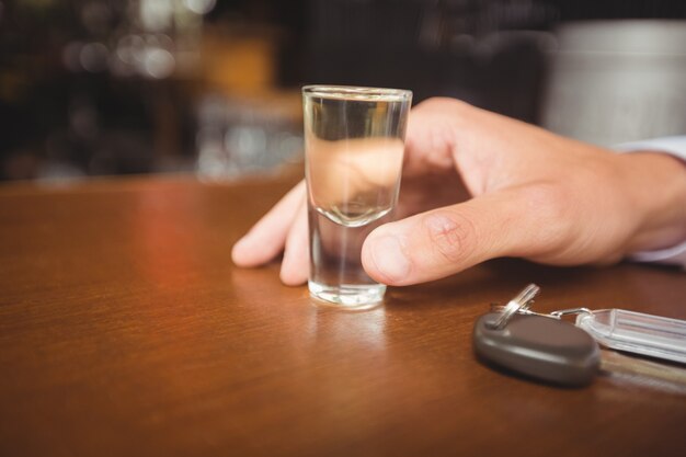 Hombre sujetando un vaso de tequila en barra de bar