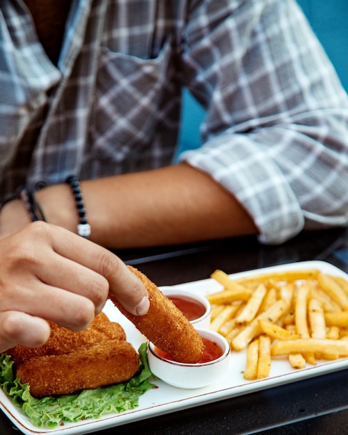 Hombre sumergiendo nugget de pollo en salsa de chile dulce