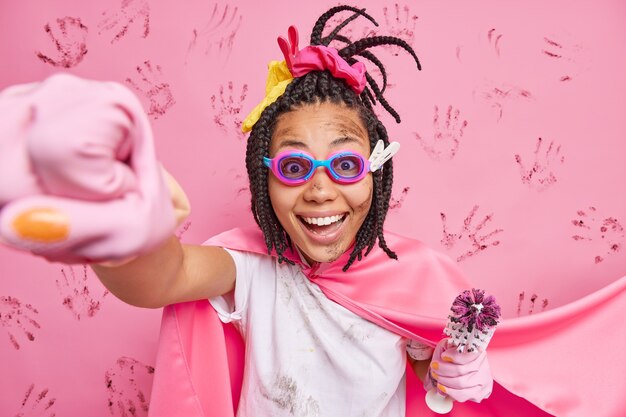 hombre superhéroe estira el brazo finge volar listo para hacer todo limpio y puro sostiene cepillo de baño sucio usa gafas capa guantes de goma