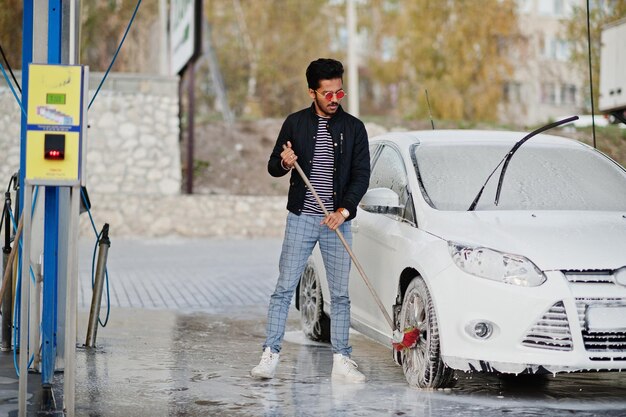 Hombre del sur de asia o hombre indio lavando su transporte blanco en lavado de autos