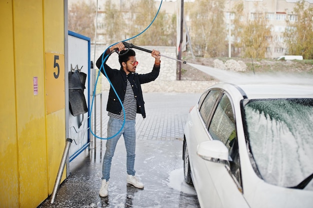 Hombre del sur de asia o hombre indio lavando su transporte blanco en lavado de autos