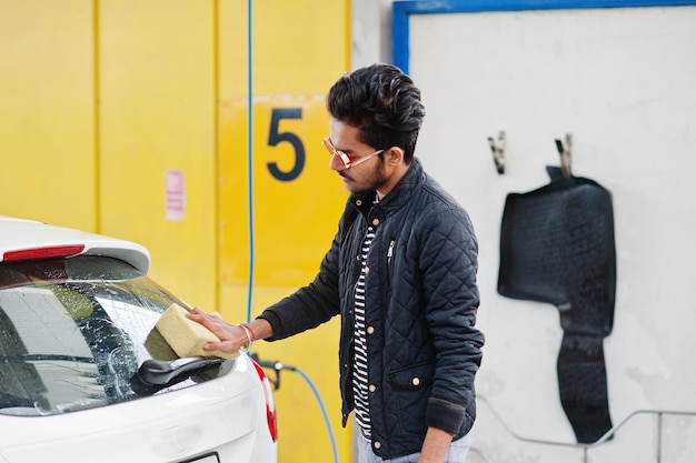 Hombre del sur de asia o hombre indio lavando su transporte blanco en lavado de autos