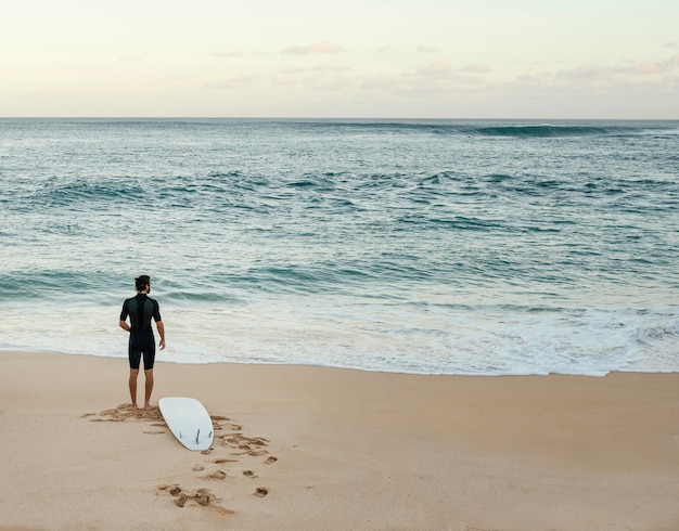 Foto gratuita hombre surfista mirando el mar horizontal tiro largo